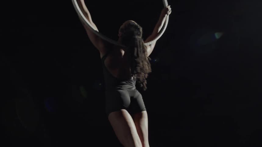 A woman swings from a suspended ring by just her head and neck