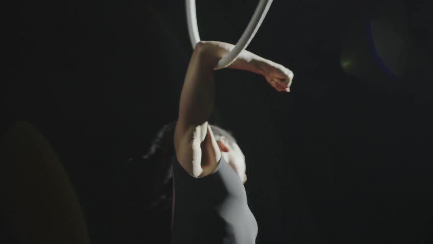Young strong fit muscular woman spinning on a ring hanging from the ceiling