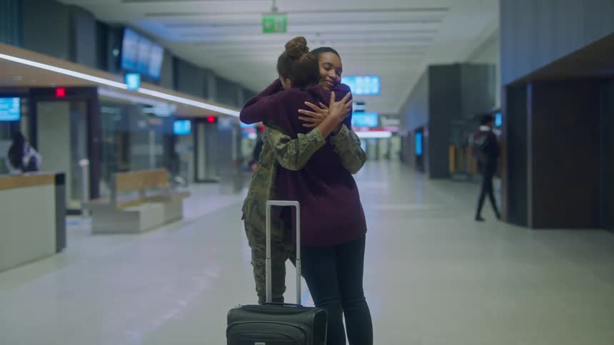 Woman greeting a military friend with a hug in the airport terminal