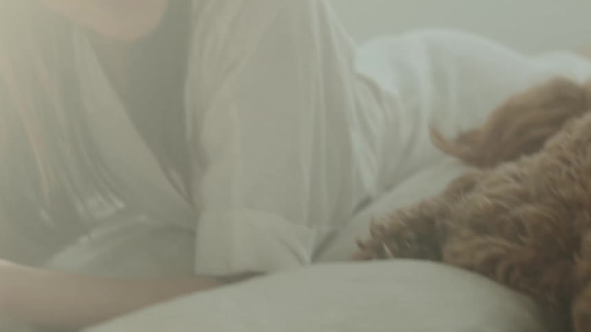 Woman lying on bed with dog