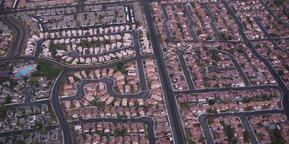 A neighborhood with houses trees streets and vehicles
