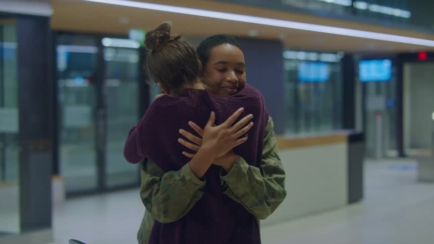 A military woman runs and hugs another woman waiting in the airport for her