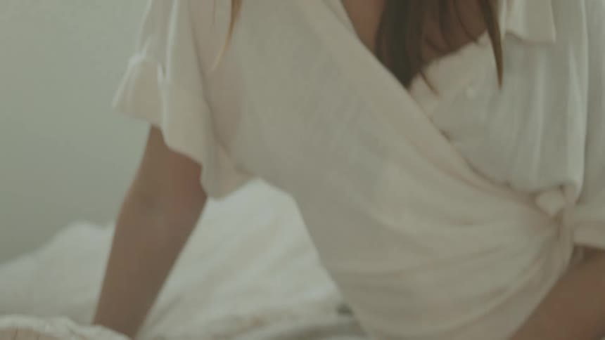 Woman sitting on bed reads thick book