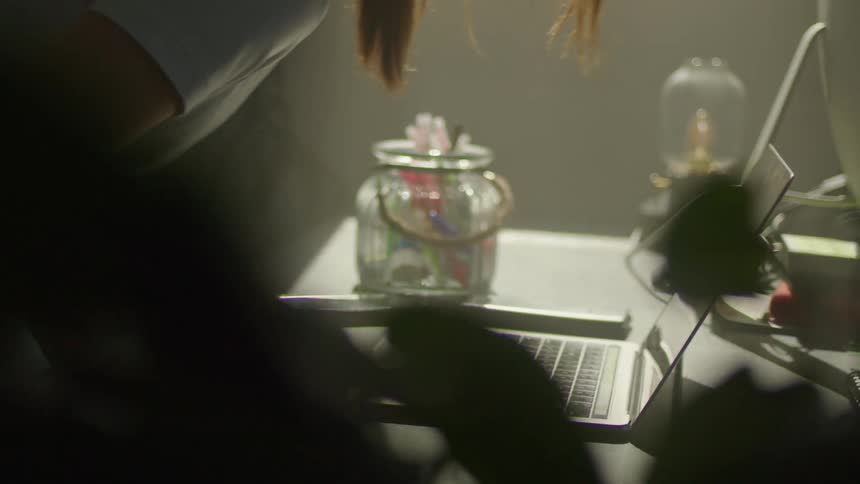 A woman sitting down at a desk with a laptop on it