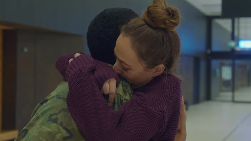 A man and woman embrace in an airport terminal