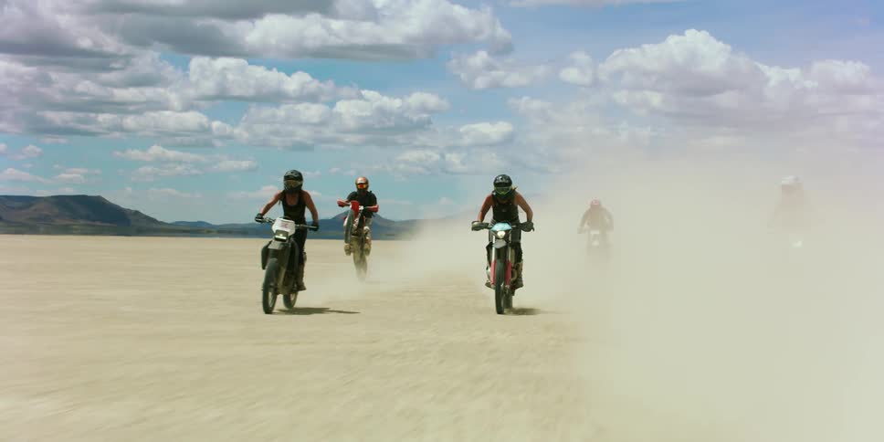 A view of a group of people riding dirt bikes on a dry lake bed