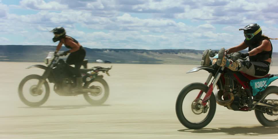 Three motorcycles speed across a salt flat