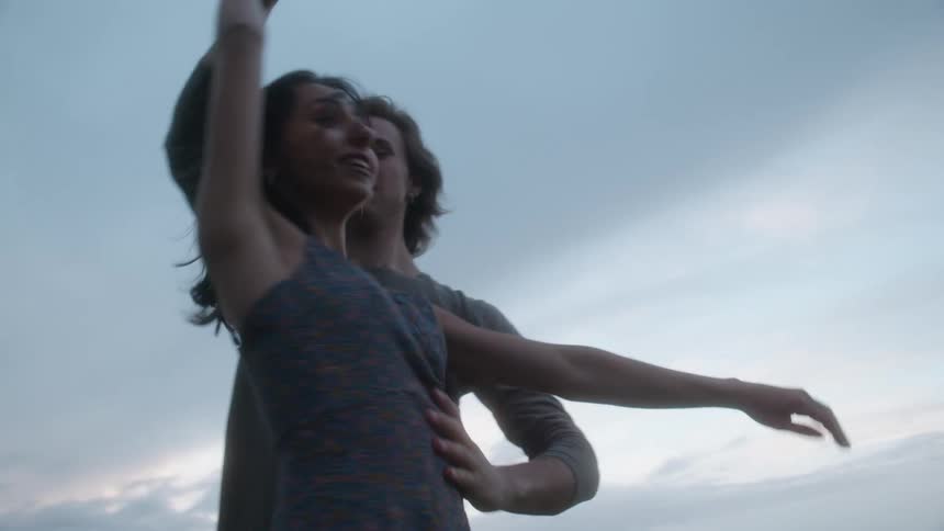 A man and woman are dancing ballet in a field