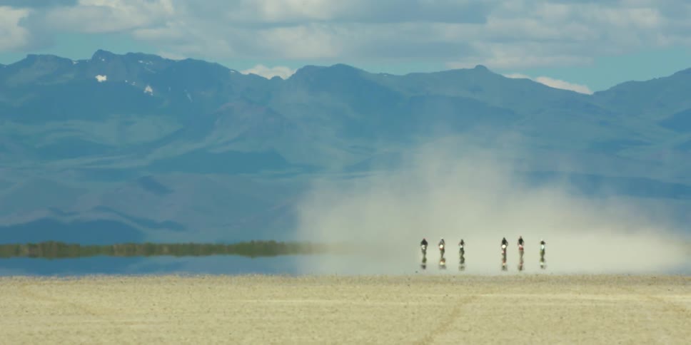 A group of motorcycles are driving in the distance
