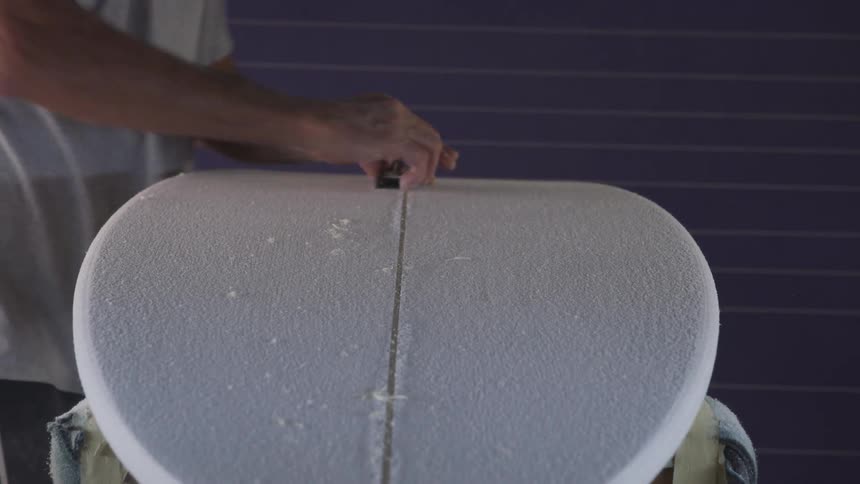 A person carving and sanding a board indoors