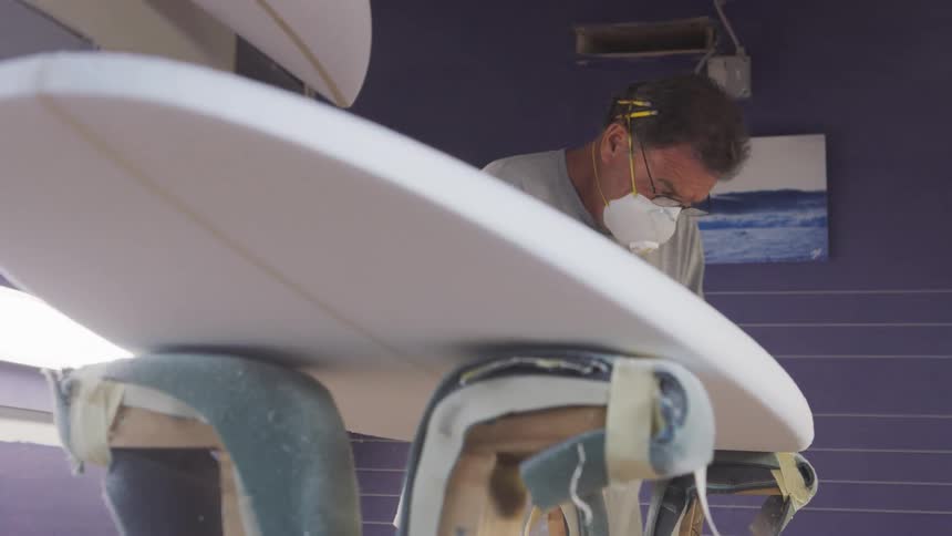 A man sanding down a surfboard