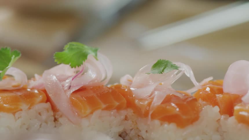 A chef is putting garnish on sushi