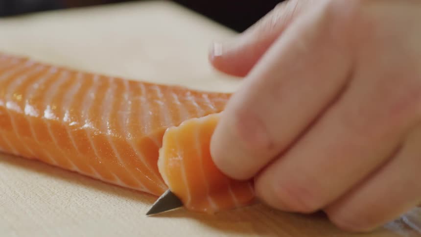 A person is cutting slices of fish