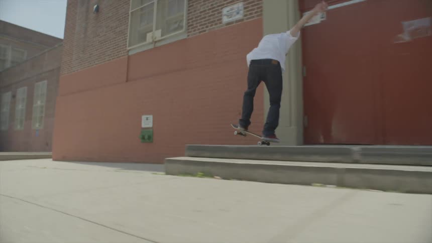 A man rides a skateboard down a sidewalk doing jumps