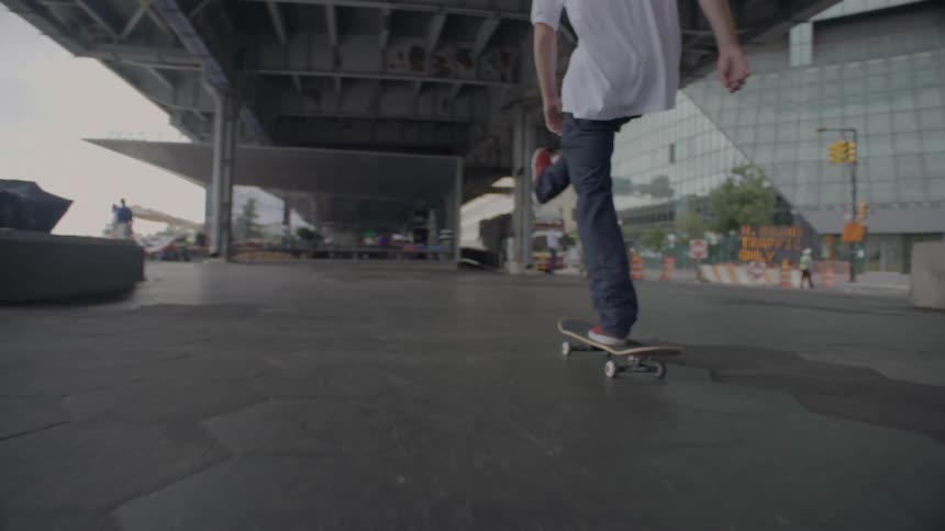 A man rides a skateboard under an overpass