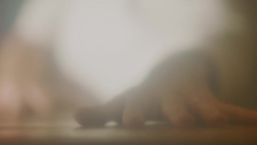 Hand resting over a wooden table inside a room at morning