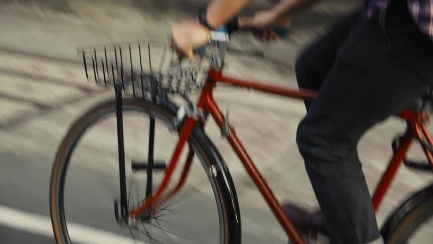 A man rides a bicycle down a city street and signals a turn with his hand