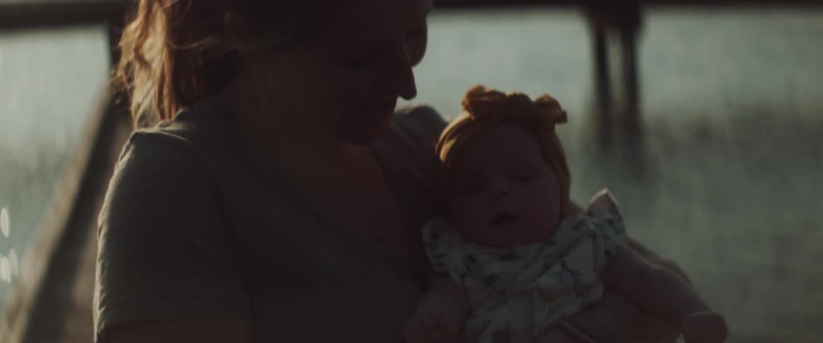 A woman holds a small baby in her arms and gently rocks it back and forth