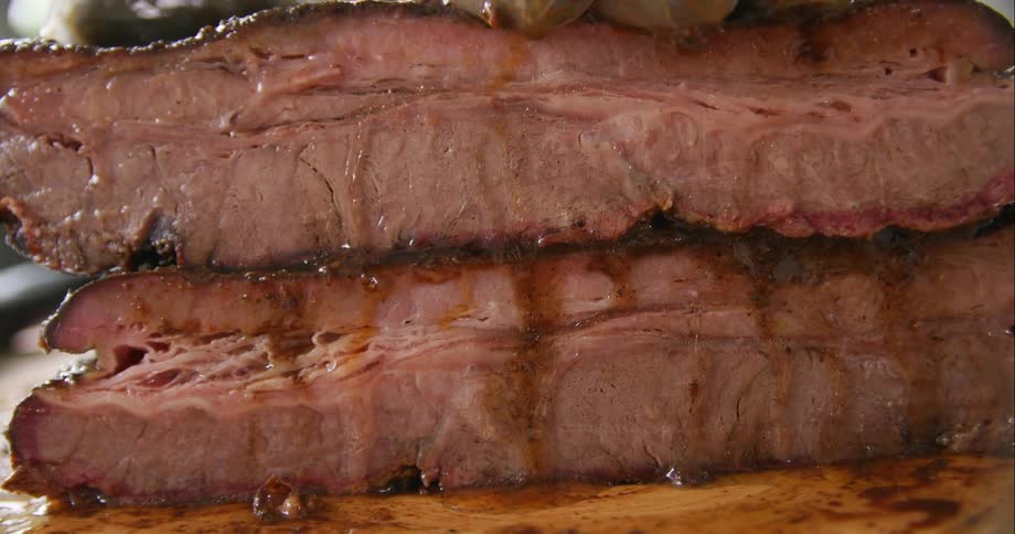 A person with gloves resting their hand on a piece of meat on a cutting board