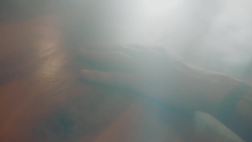 Hand of a tattoed man resting on the wooden table inside a room at morning