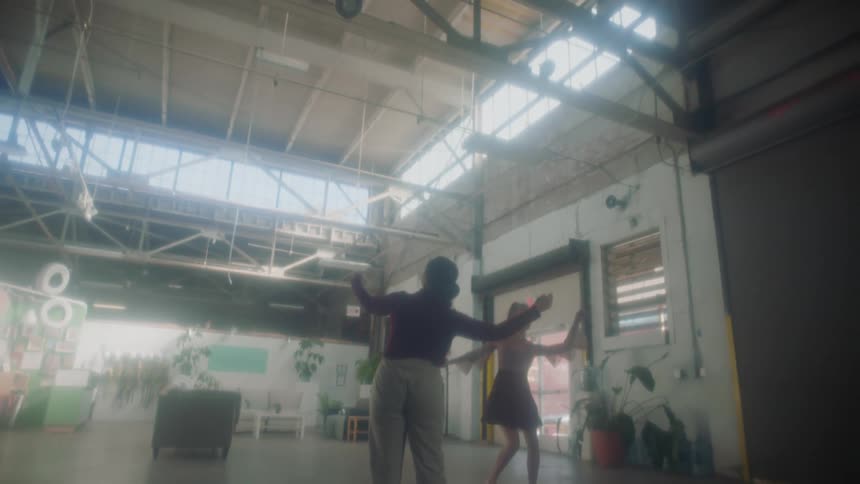 Two women danicing inside a warehouse in the morning
