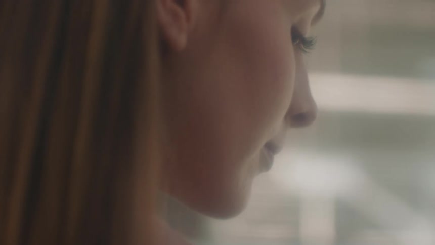 A woman in a room with a wall in the background