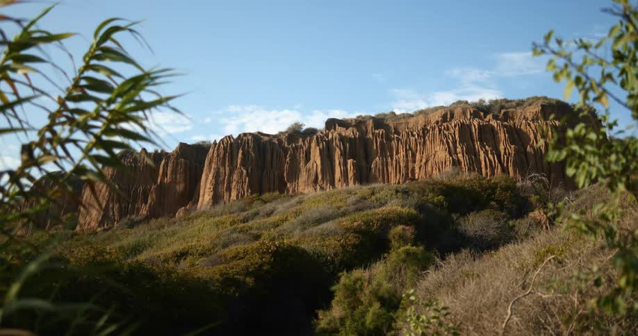 A landscape with hills and cliffs with the sky and clouds in the background