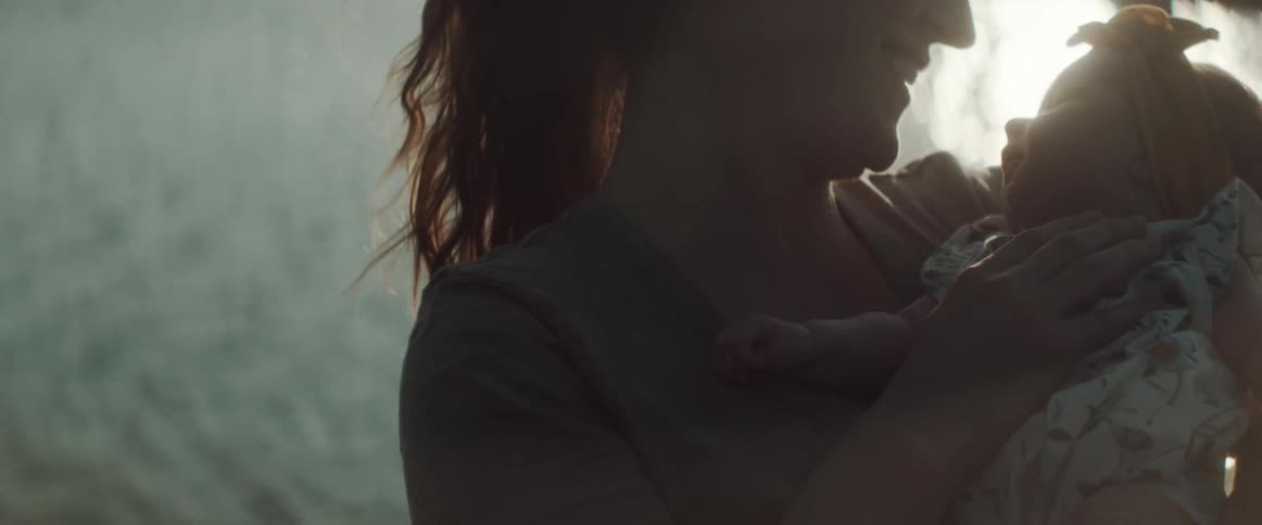 A woman smiles as she holds and kisses her infant daughter