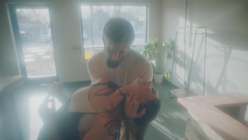 Young couple slowly dancing inside a shop in a small town