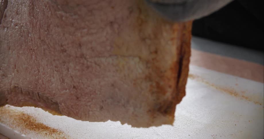 A person flips over a piece of meat that has been coated in seasoning