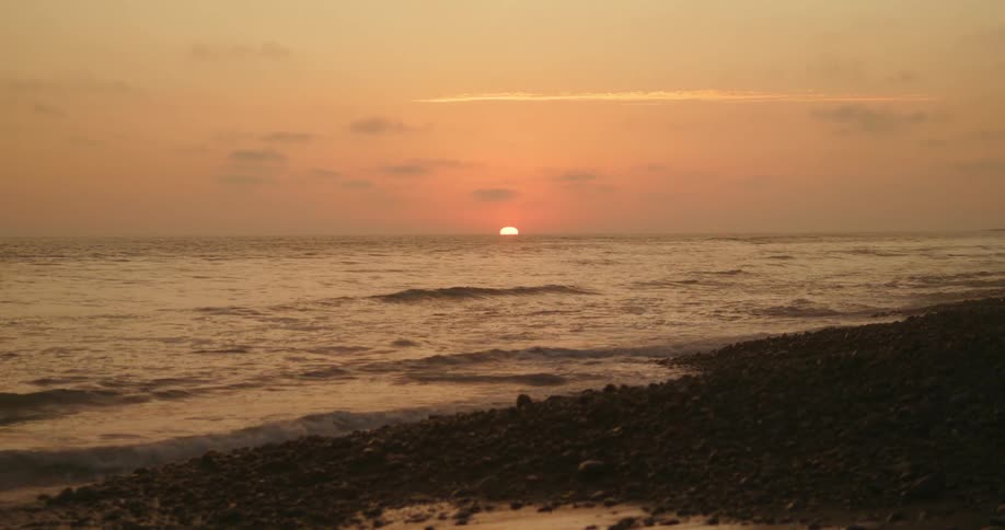 The sun is just barely above the horizon as it shines upon an ocean beach