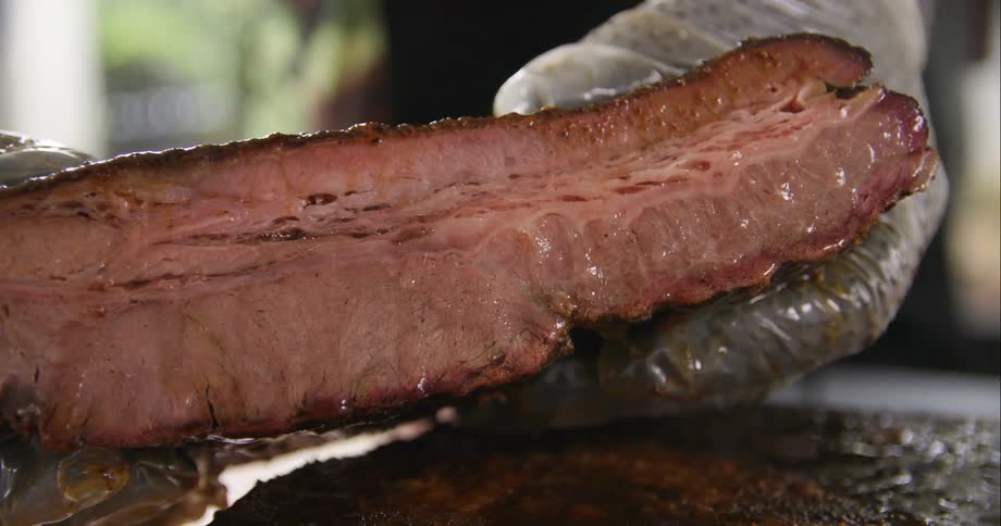 A person holding a piece of meat outdoors
