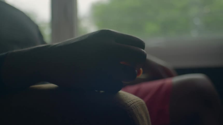 A person sitting in a chair slowly runs their fingers along the armrest