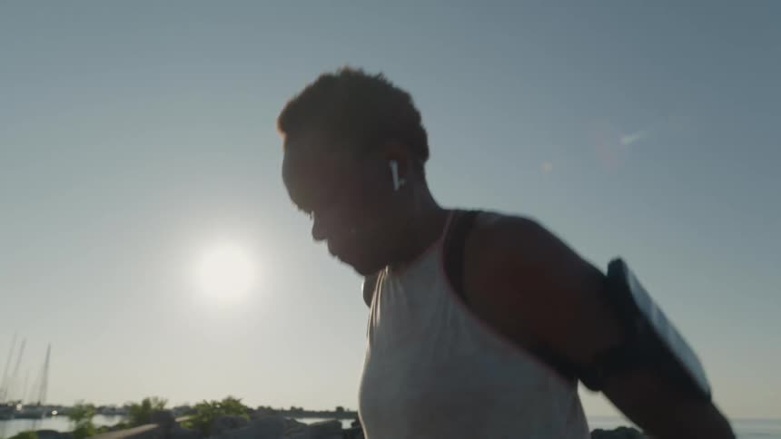 Women wearing air pods stand outside and stretches well in the middle of exercising