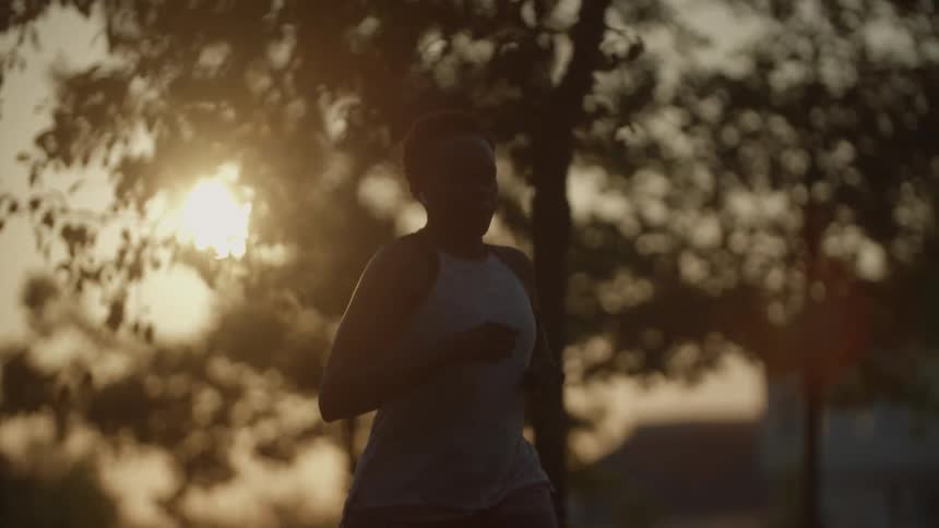 Silhouette of a young woman jogging on the streets at sunset