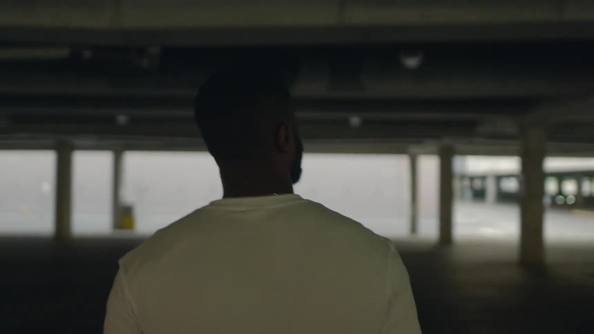 A man walks through an empty parking garage