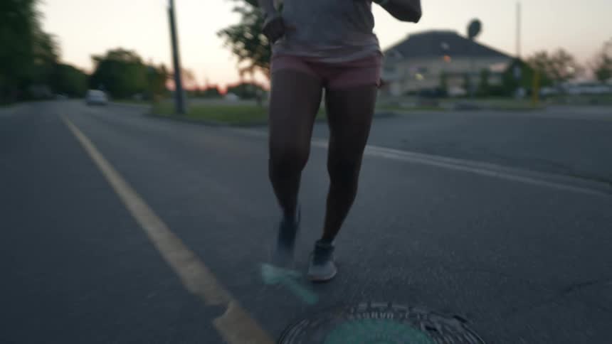 A woman is doing a morning jog in a residential area during the early morning