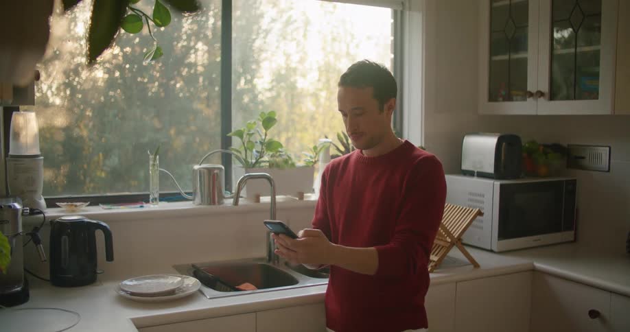 A man is using his cell phone by the sink