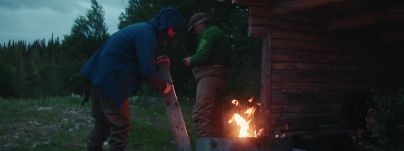 Two men are standing by a bonfire