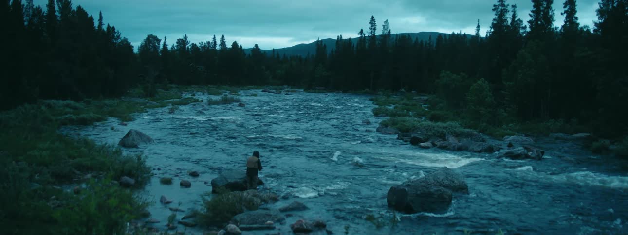 A man is fishing in the rough stream