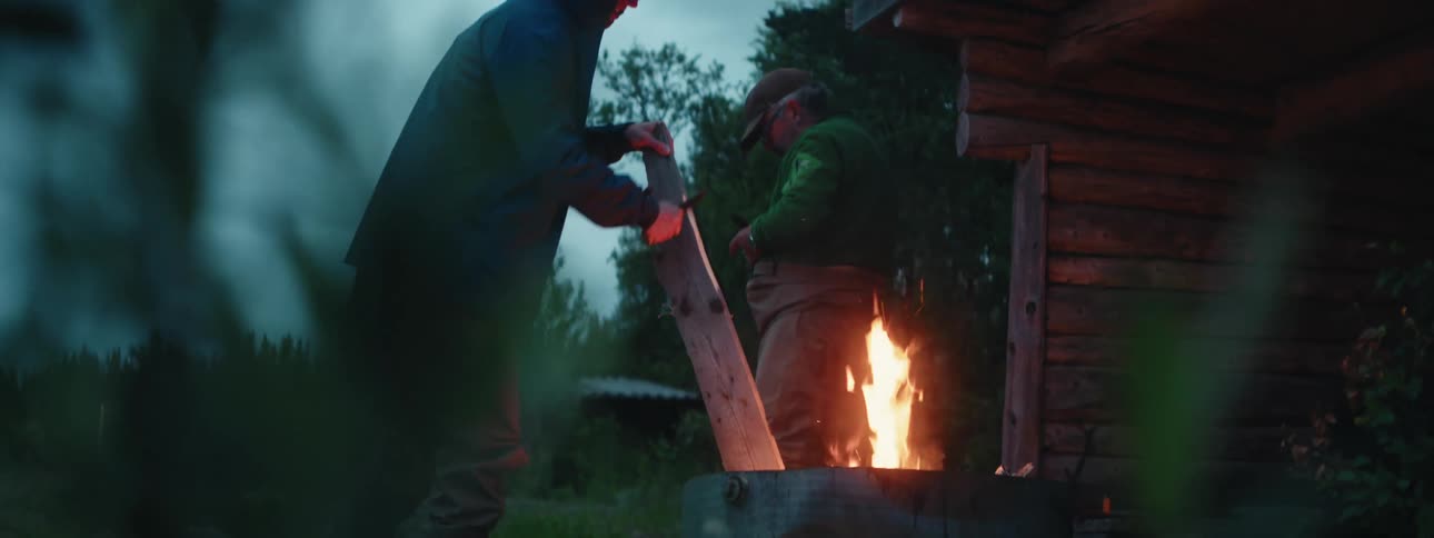 Two men are preparing by a campfire