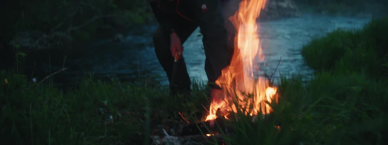 A man is adding branches to a fire