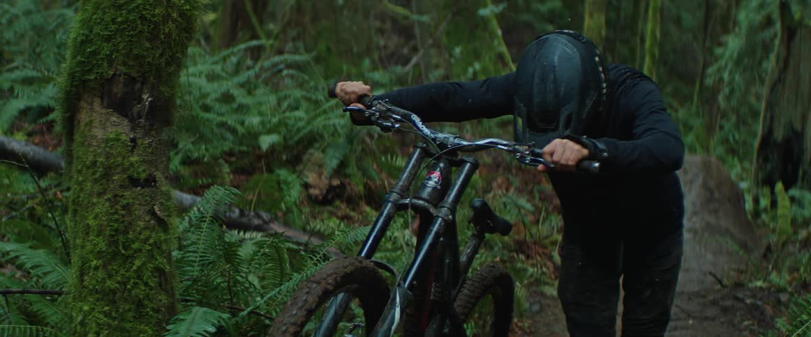 A man pushes a mountain bike through the mud