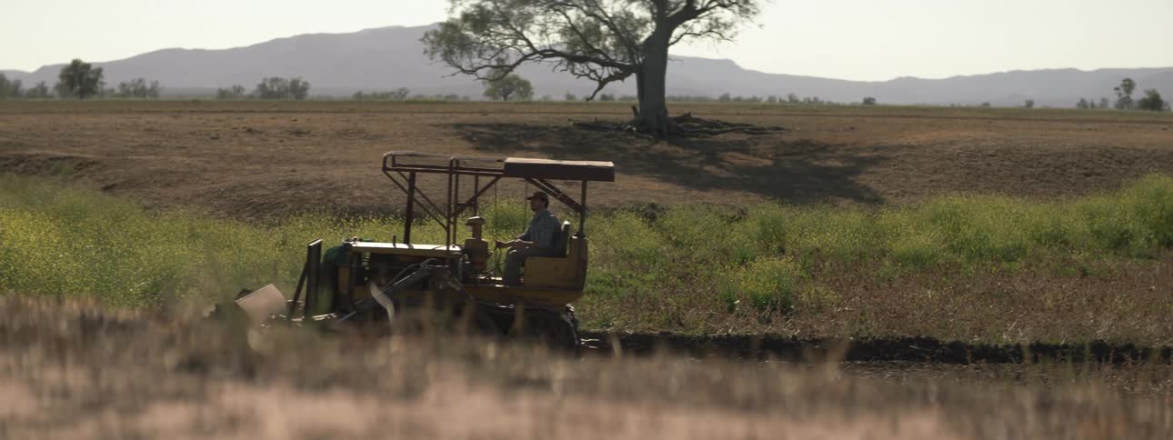A man drives a tractor through an open field