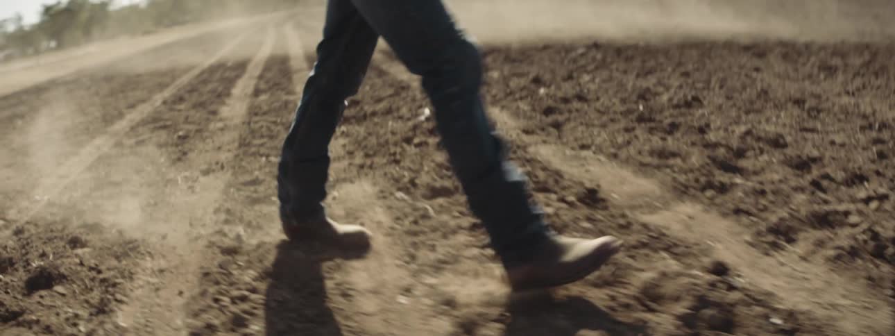 A person walking on dirt wearing boots