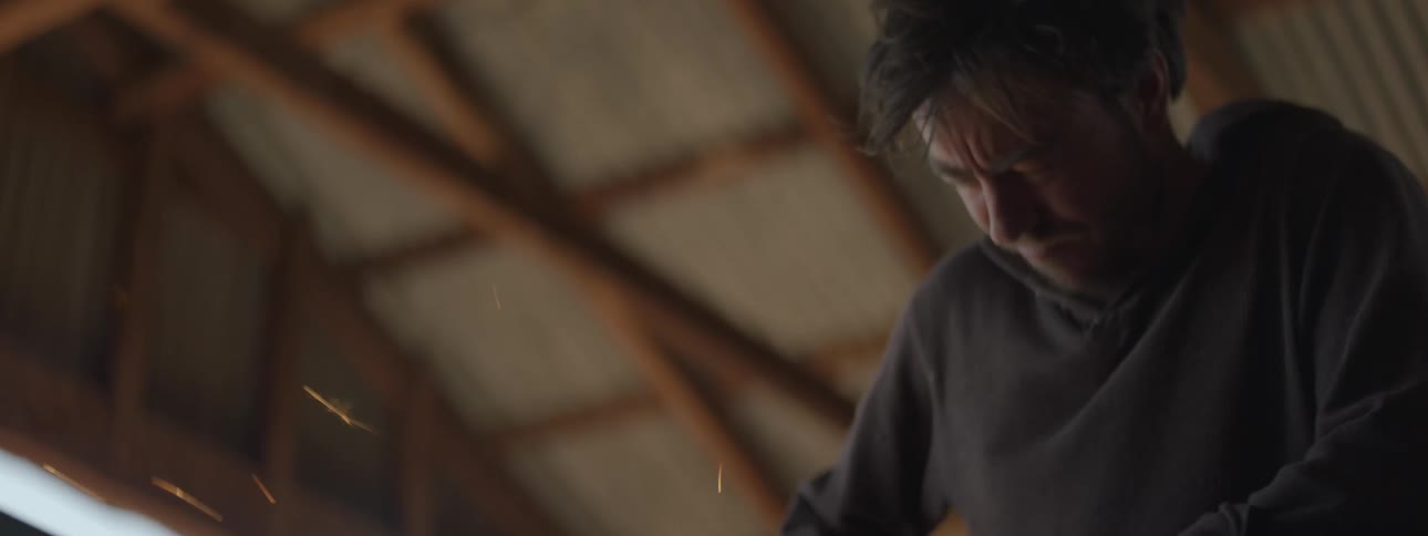A man is working using a tool on metal