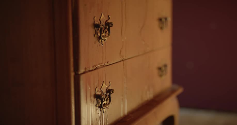 An old painted wooden dresser sits in a room with water dripping down it
