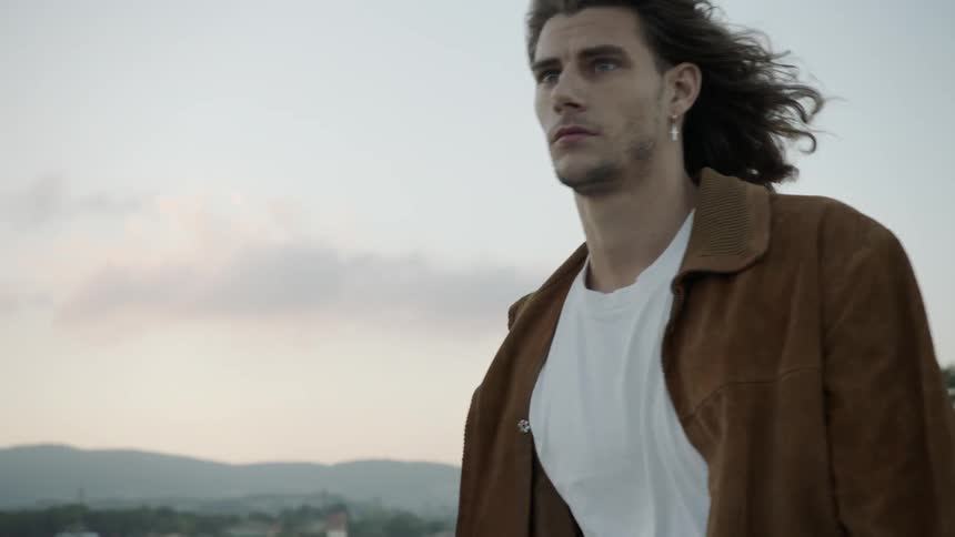 A man walks forward with wind blowing his hair