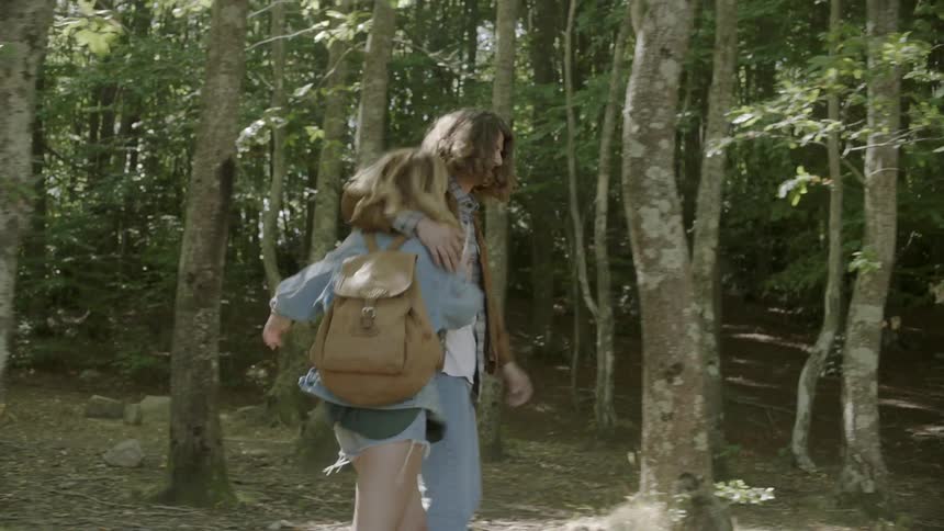A and women play pushing each other and hiking in the woods