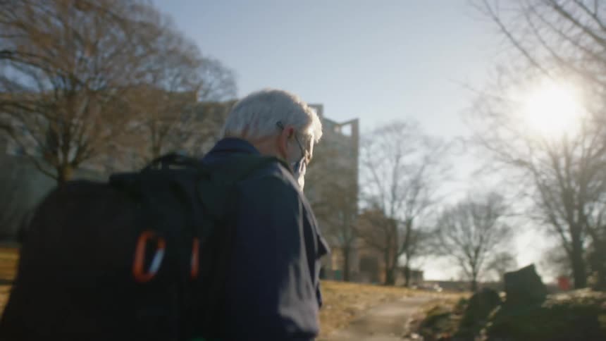 A professor walks through campus with his backpack